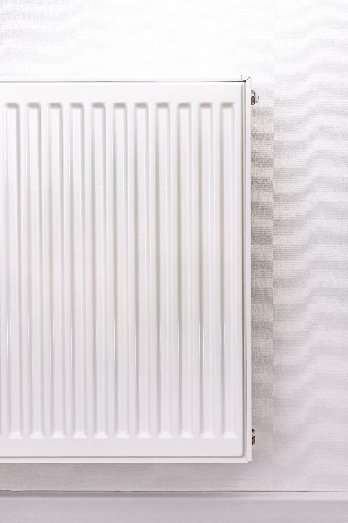 White metal radiator against a light wall. Minimalistic heating element in a modern interior. Clean and simple design with a neutral color palette White metal radiator against a light wall. Minimalistic heating element in a modern interior. Clean and simple design with a neutral color palette